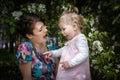 Mother and daughter have fun in the park and apple tree with white flowers Royalty Free Stock Photo
