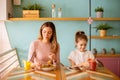 Mother and daughter having a breakfast with fresh squeezed juices in the cafe Royalty Free Stock Photo