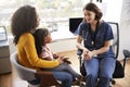 Mother And Daughter Having Consultation With Female Pediatrician Wearing Scrubs In Hospital Office Royalty Free Stock Photo