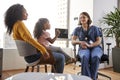 Mother And Daughter Having Consultation With Female Pediatrician Wearing Scrubs In Hospital Office Royalty Free Stock Photo