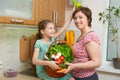 Mother and daughter having fun with basket of vegetables and fresh fruits in kitchen interior. Parent and child. Healthy food conc Royalty Free Stock Photo