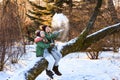 Mother and daughter having fun, playing, throwing snow and laughing in winter wood outdoor.