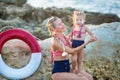 Mother daughter having fun resting on the rocky beach. Two blond lady wearing retro swimming suits enjoy summer day together Royalty Free Stock Photo