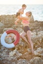 Mother daughter having fun resting on the rocky beach. Two blond lady wearing retro swimming suits enjoy summer day together Royalty Free Stock Photo