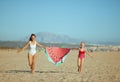 Mother and daughter holding funny watermelon towel and running