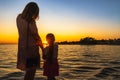 Mother and daughter holding hands, admiring beautiful sunset at Adriatic Sea beach Royalty Free Stock Photo