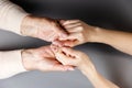 Mother and daughter holding hands. Close-up. Flat lay. Gray background. The concept of caring for pensioners