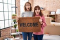 Mother and daughter holding welcome doormat afraid and shocked with surprise and amazed expression, fear and excited face Royalty Free Stock Photo