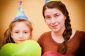 Mother and daughter on holiday with balloons in a cap with the inscription Happy Birthday