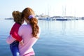 Mother and daughter hug looking blue marina