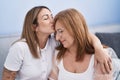 Mother and daughter hugging each other and kissing sitting on sofa at home Royalty Free Stock Photo