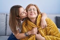 Mother and daughter hugging each other and kissing sitting on sofa at home Royalty Free Stock Photo