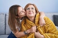 Mother and daughter hugging each other and kissing sitting on sofa at home Royalty Free Stock Photo