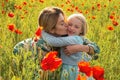 Mother and daughter hugging on flowering poppy field. Summer family holidays on nature. Summer on poppies meadow with Royalty Free Stock Photo