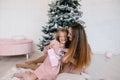 Mother and daughter hugging at home near Christmas tree. woman and girl with a Christmas present Royalty Free Stock Photo