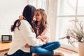 Mother and daughter hugging on kitchen window sill by decorated Christmas tree. Family spending time together at home Royalty Free Stock Photo
