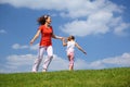 Mother with daughter hurry and play on grass