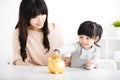 mother and daughter Inserting Coin In Piggy bank