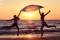 Mother and daughter jumping on the beach at the sunset time. Royalty Free Stock Photo