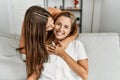 Mother and daughter kissing and hugging each other sitting on sofa at home Royalty Free Stock Photo