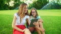 Mother and daughter laughing in park. Woman and girl talking at camera on tablet Royalty Free Stock Photo
