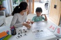 Mother and daughter learning to read and write letter at home