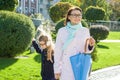 Mother and daughter little girl an elementary school student holding hands go to school. Autumn city background Royalty Free Stock Photo