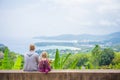 Mother and daughter look around from mountain view point on tropical beach island