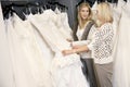 Mother and daughter looking at each other while selecting wedding gown in bridal store