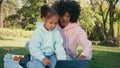 Mother daughter looking tablet on green meadow close up. African family picnic Royalty Free Stock Photo