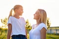 Mother and daughter looks on each other in countryside in sunset in summer. Royalty Free Stock Photo