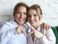 Mother and daughter love. Adult woman and young woman stacking hands in heart sign looking at camera. Royalty Free Stock Photo