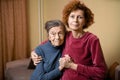 Mother and daughter, mature woman with red hair and elderly old cute happy lady woman with gray hair and deep wrinkles, embrace