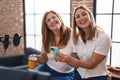 Mother and daughter musicians using smartphone drinking coffee at music studio