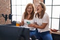 Mother and daughter musicians using smartphone drinking coffee at music studio