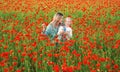 Mother with daughter outdoor in poppy field. Mom hugs lovely child on poppies background. Family in the field of spring