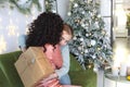 Mother and little daughter in pajamas embracing while exchanging Christmas gifts in morning