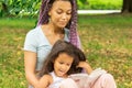 Mother and daughter in the park reading a book, african family woman and girl sitting on the grass, home schooling Royalty Free Stock Photo