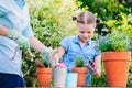 Mother and daughter planting flowers in pots in the garden