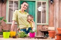 Mother and daughter with plants and flowerpots standing and hugging at table on porch