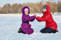 Mother and daughter play sitting in snow on bright