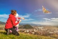 Mother and daughter playfull with kite in field over town