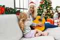 Mother and daughter playing guitar and singing sitting by christmas tree at home Royalty Free Stock Photo