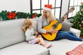 Mother and daughter playing guitar and singing sitting by christmas tree at home Royalty Free Stock Photo