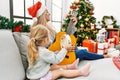 Mother and daughter playing guitar and tambourine sitting by christmas tree at home Royalty Free Stock Photo