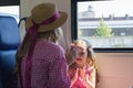 Mother and daughter playing patty-cake sitting near window of moving speed train Royalty Free Stock Photo