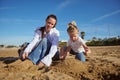 Mother and daughter playing together on the beach, building sandy castle