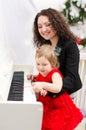 Mother and daughter playing on white piano Royalty Free Stock Photo