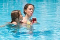 Mother and daughter in the pool and drinking juice. Royalty Free Stock Photo