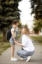 Mother and daughter pupil walking to school. Mom leads little school child first day at school